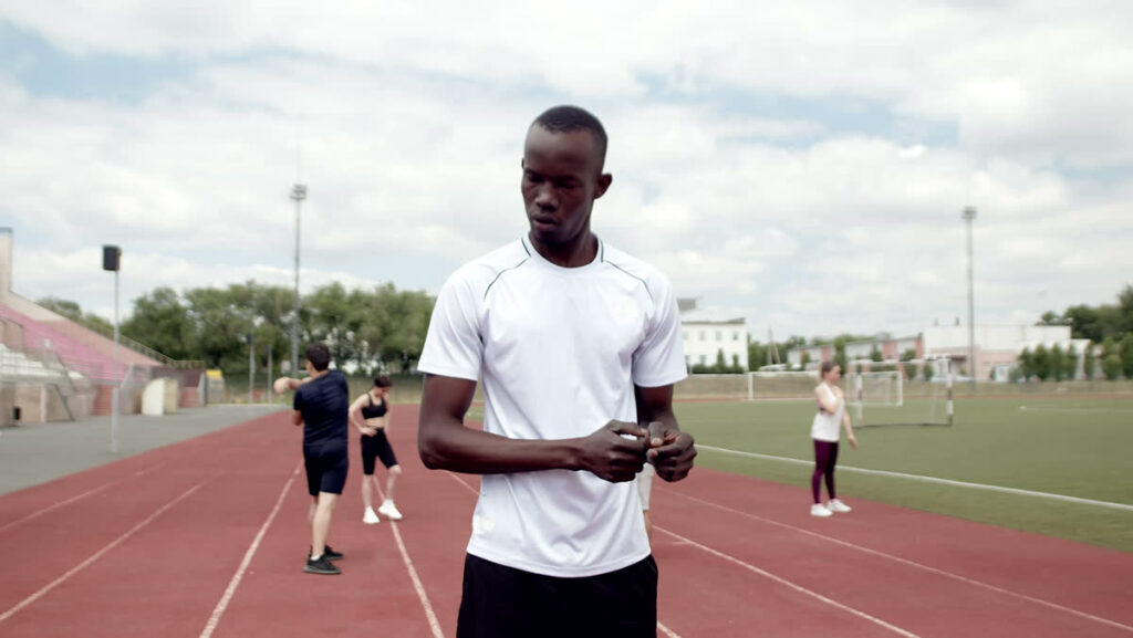 A man on a running track holds and checks his wrist