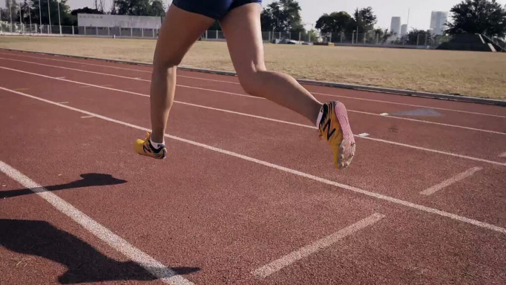 Close-up of a runner's legs and feet mid-stride on a running track