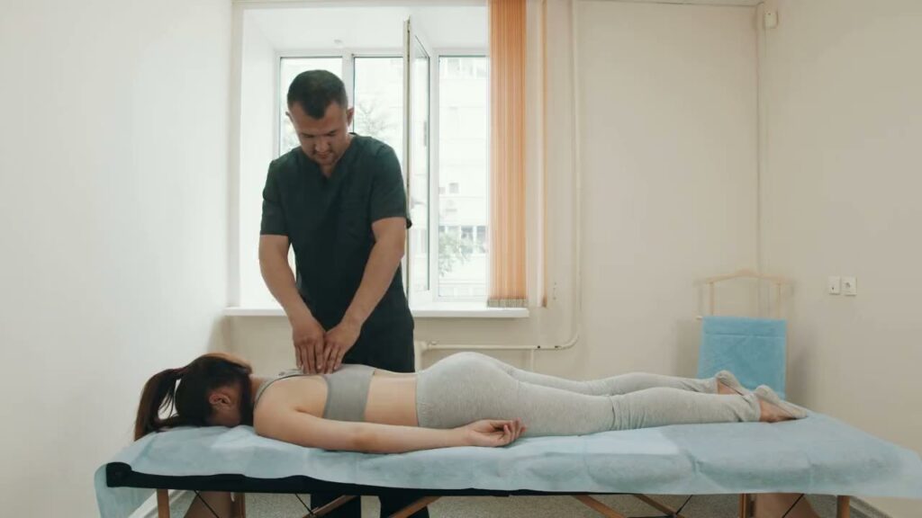 A Physiotherapist treats the back of a patient lying on a treatment table